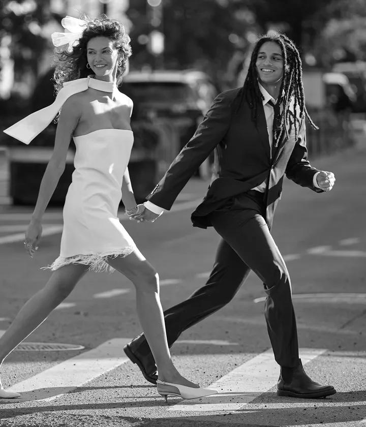 Image of a newly wed couple walking hand in hand through a city street. 20% of Bridal.