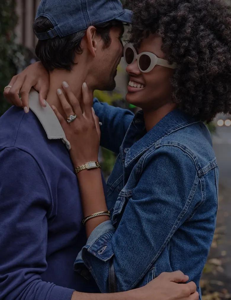 Image of a couple hugging and smiling in a city street wearing Helzberg jewelry. Clearance up to 50% off.