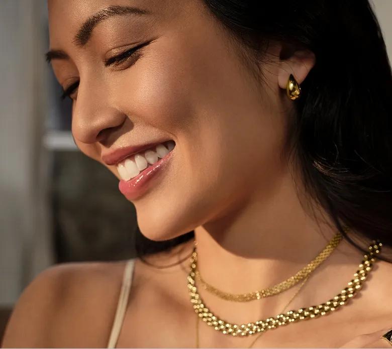 Image of a woman wearing multiple gold necklaces.